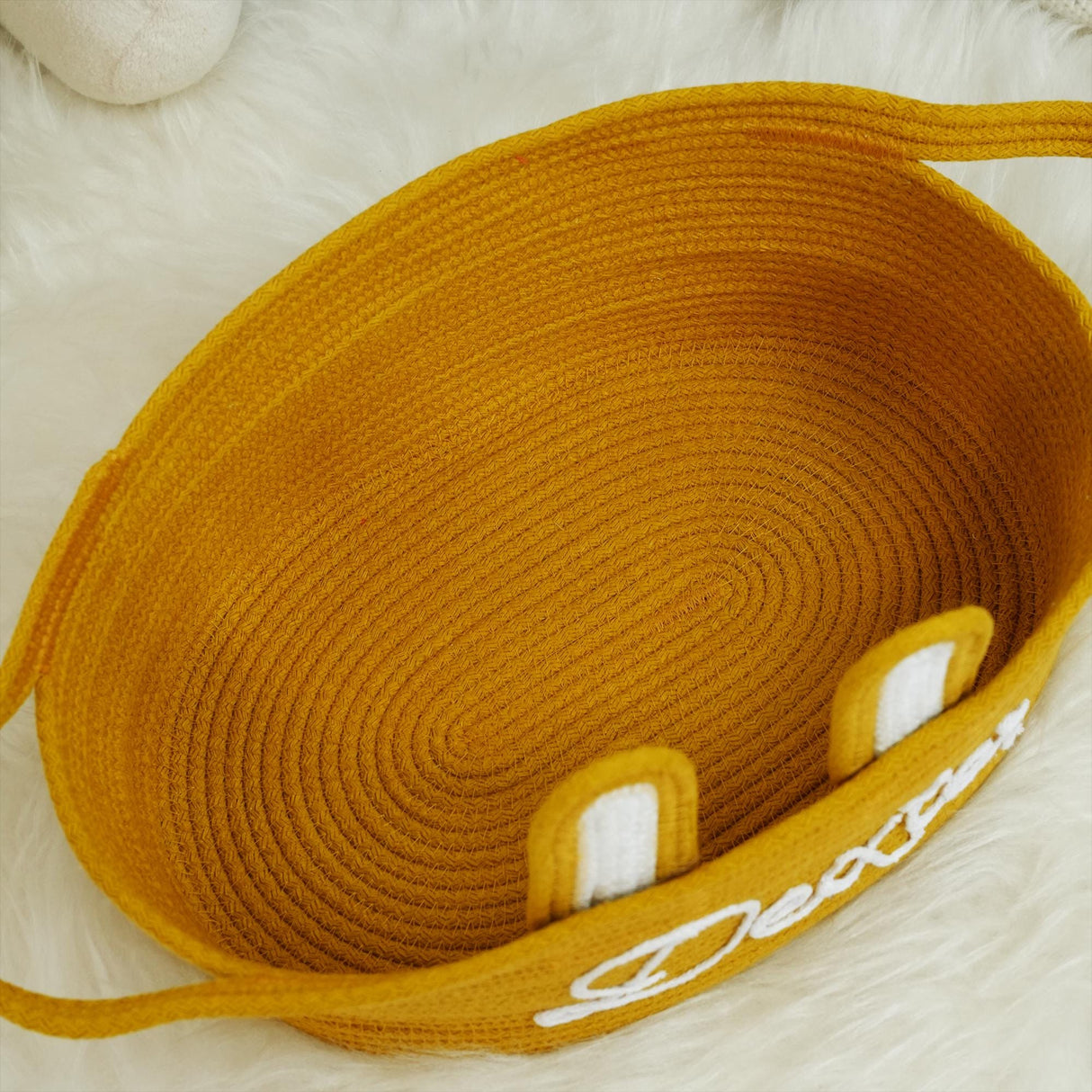 a yellow basket with two white handles on a white rug