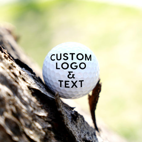 Golf ball with 'CUSTOM LOGO & TEXT' text on a blurred natural background