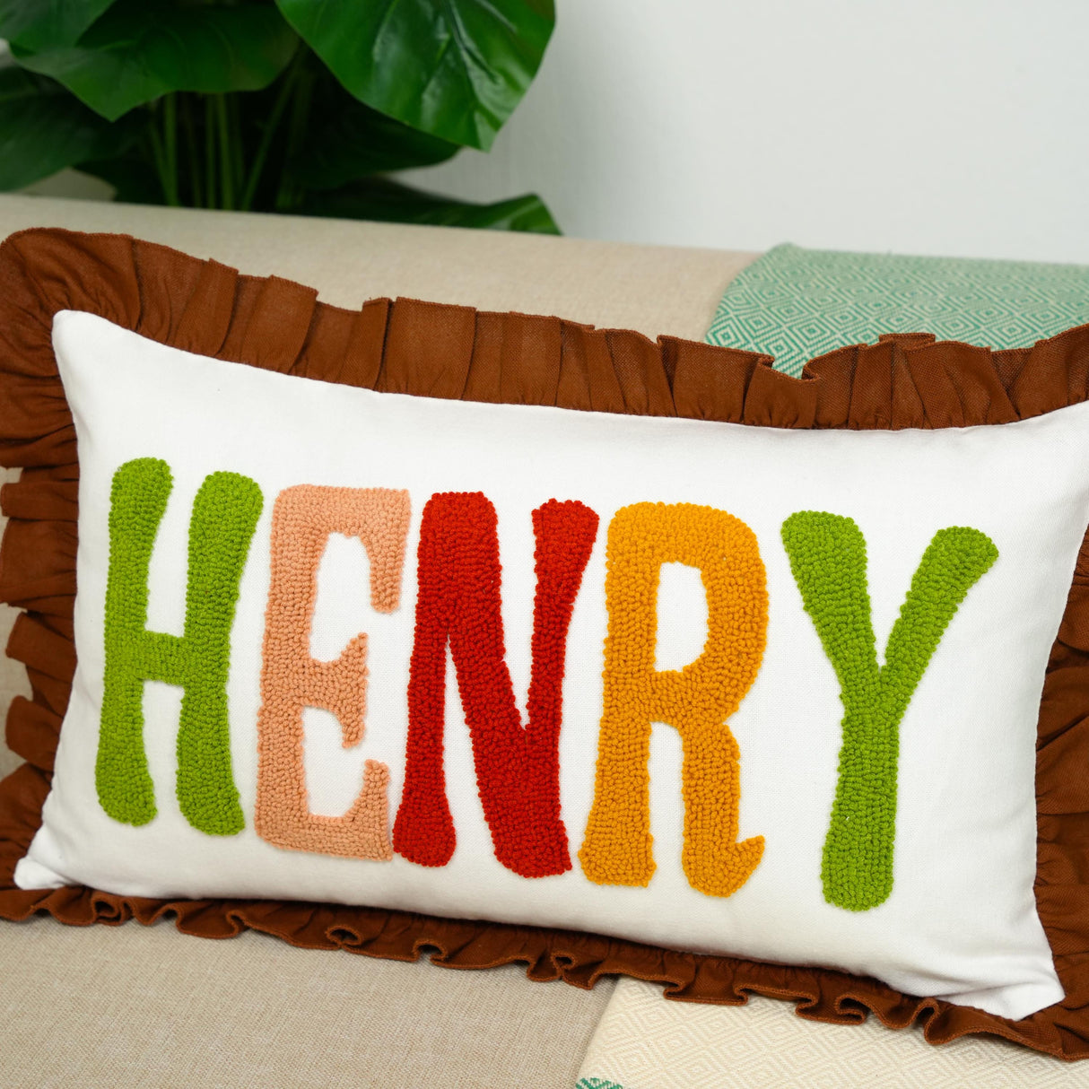 A decorative throw pillow with the name "HENRY" embroidered on it in colorful letters.