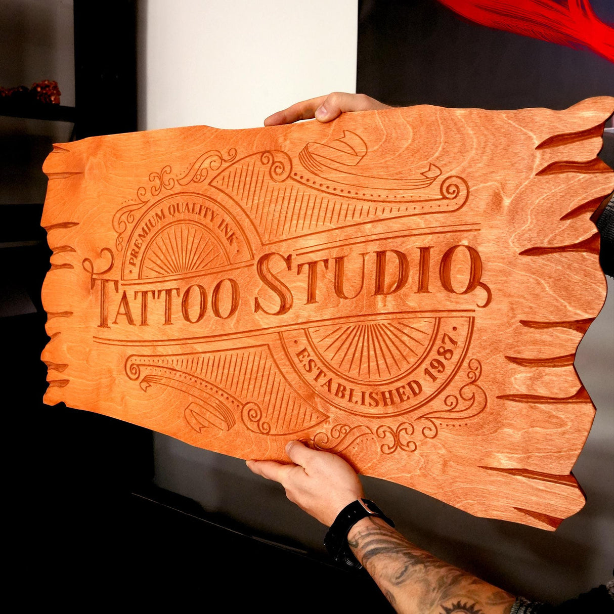 a person holding a wooden sign that says tattoo studio