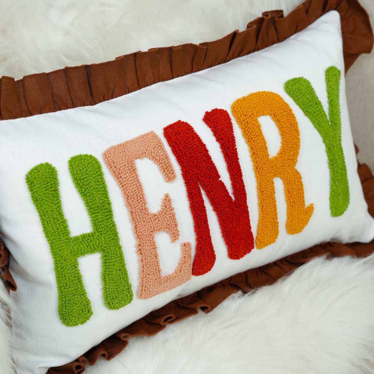 A decorative pillow with the name "HENRY" embroidered in colorful letters.