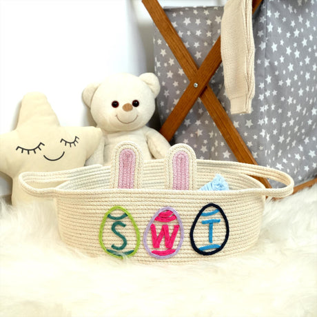 a teddy bear sitting next to a basket with a name on it