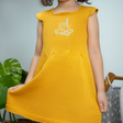 a girl in a mustard dress holding the hem of her skirts