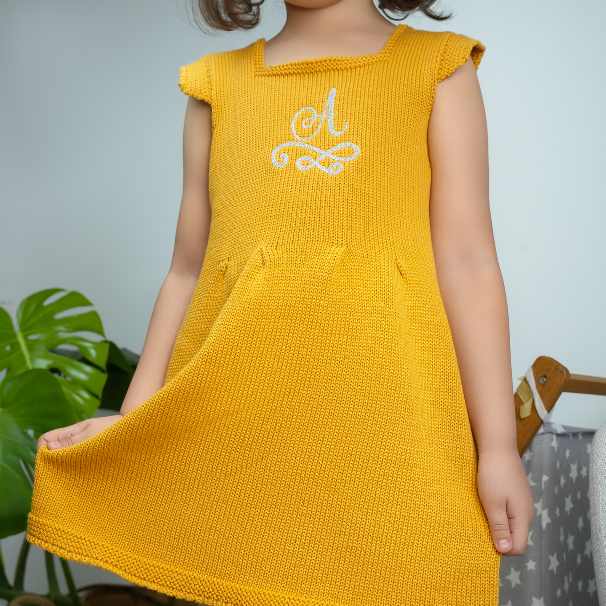a girl in a mustard dress holding the hem of her skirts