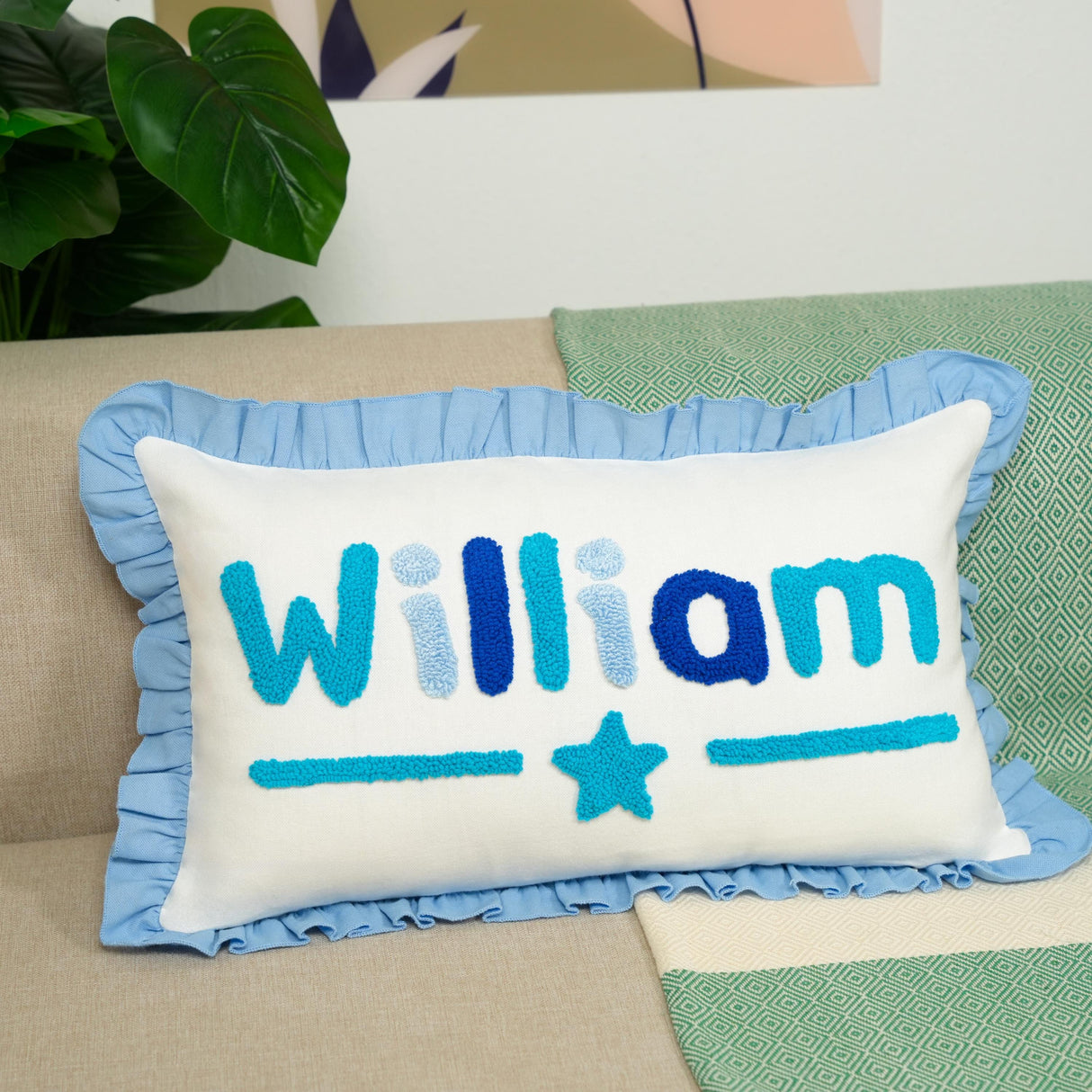 A white pillow with blue text and a blue star on it, placed on a couch.