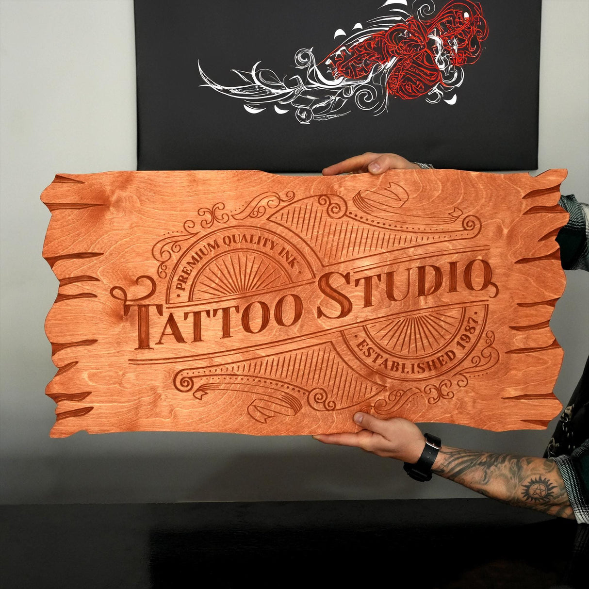 a person holding a wooden sign that says tattoo studio