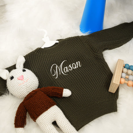 a knitted cat laying on top of a white rug