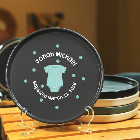 a black plate with a baby's t - shirt on it