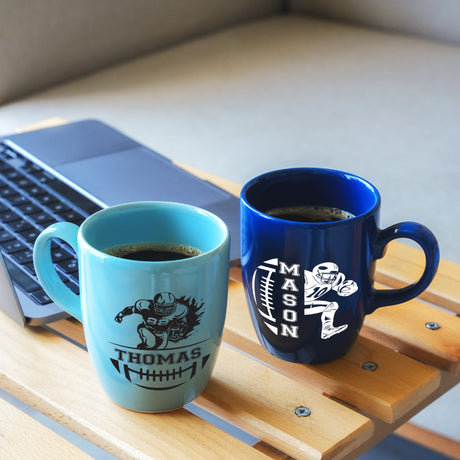 two coffee mugs sitting on a table next to a laptop