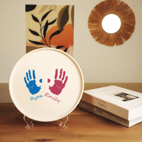 a plate with two hand prints on it next to a book