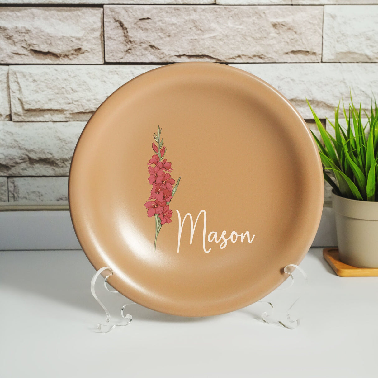 a plate with a flower on it sitting next to a potted plant
