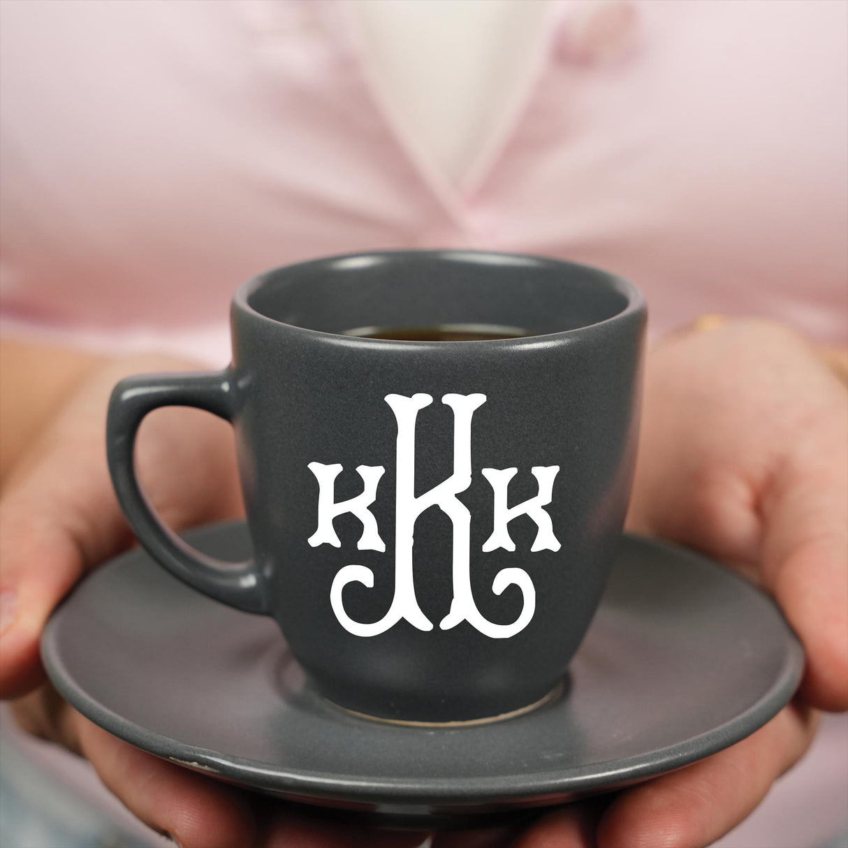 a person holding a cup of coffee with the letter h on it