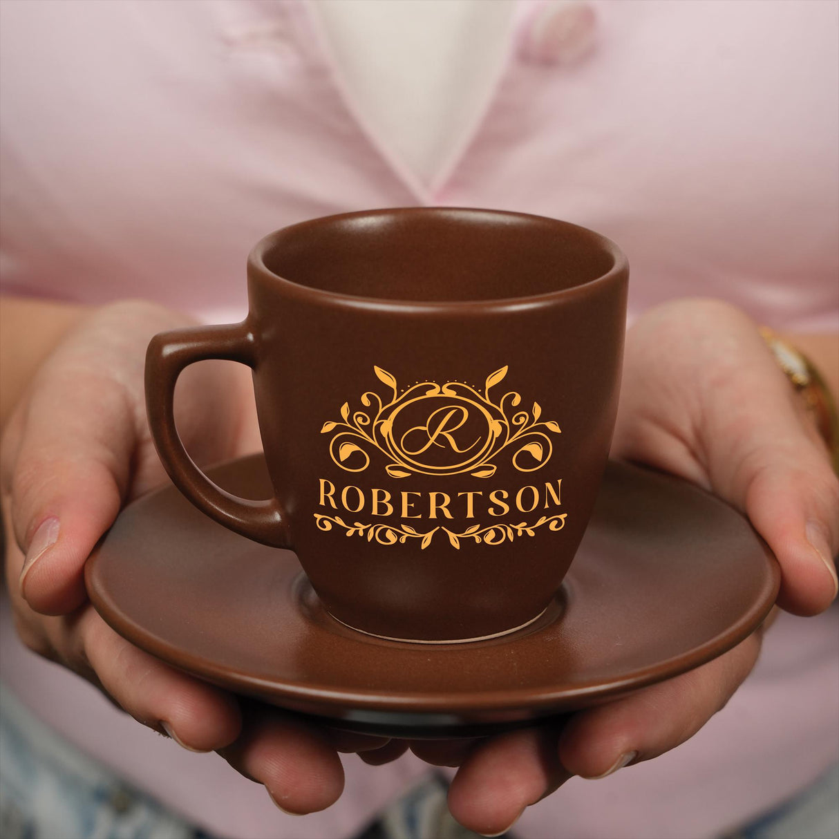 a person holding a brown coffee cup on a saucer