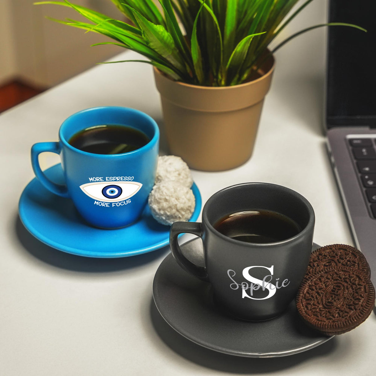 a cup of coffee next to a laptop on a desk