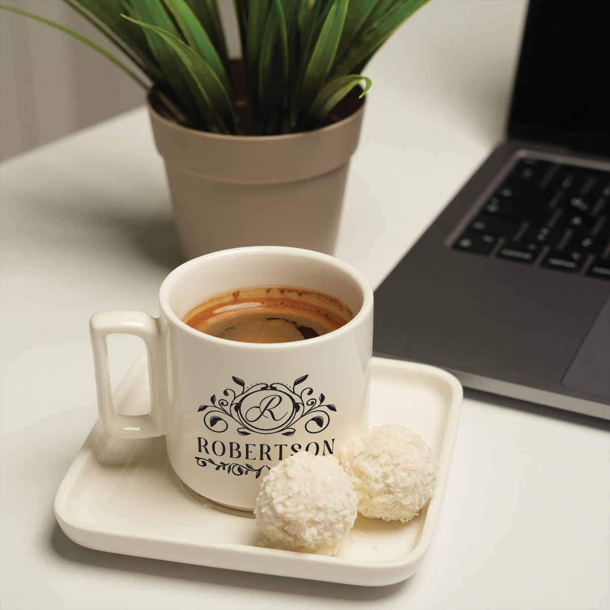 a cup of coffee on a tray next to a laptop