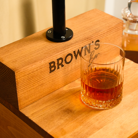 Glass of whiskey on a wooden coaster with 'Brown's' branding.