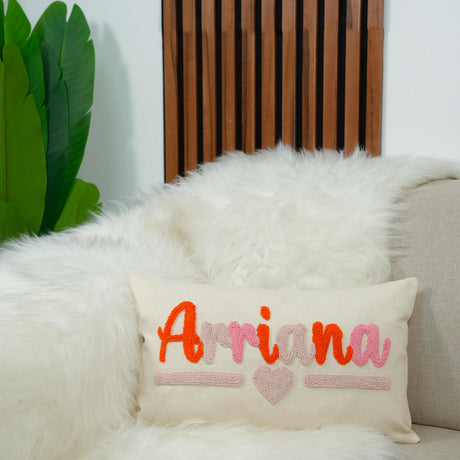 A white fur throw pillow with the word &quot;Arriana&quot; embroidered on it, placed on a white couch.