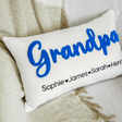 a white pillow with a blue embroidered name on it