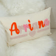 A white pillow with the name &quot;Ariaana&quot; embroidered on it in pink and orange colors.