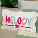 A white pillow with the word &quot;Melody&quot; embroidered on it, sitting on a couch.