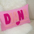 A pink pillow with the name &quot;DIANA&quot; embroidered on it, along with a heart symbol.