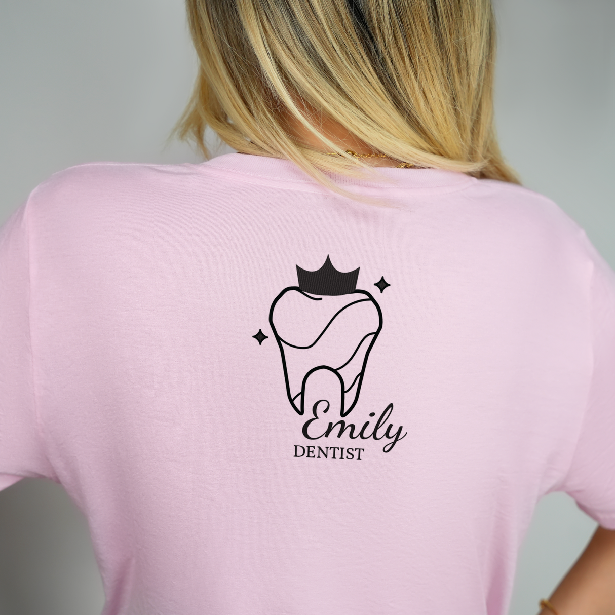 back view of a woman with blond hair wearing a pink dentist T-shirt