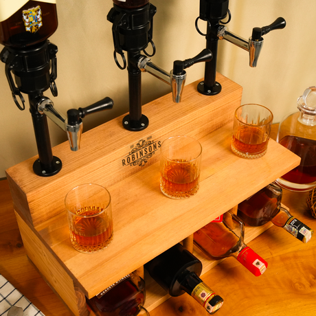 Wooden drink dispenser with glasses and bottles on a wooden surface