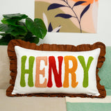 A decorative throw pillow with the name &quot;HENRY&quot; embroidered on it, placed on a couch.