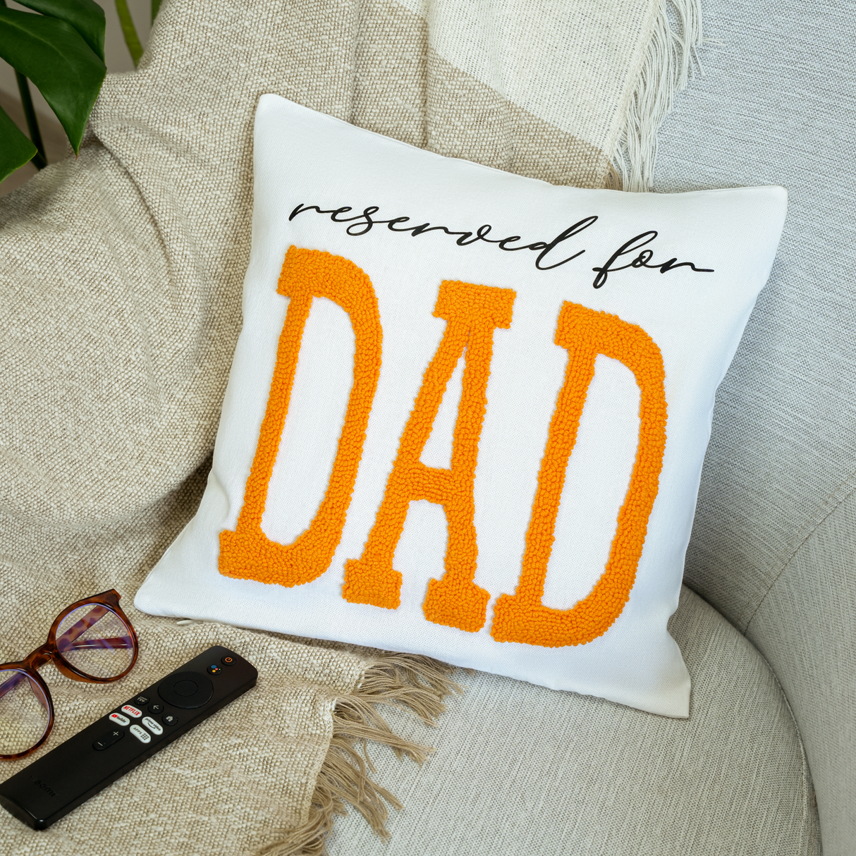 a pillow with the words reserved for dad on it next to a pair of glasses