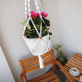 a white hanging planter with pink flowers in it