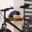 close-up of a wall-mounted bicycle holder with bicycle and helmet on it