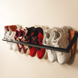 a shoe rack hanging on the wall with four shoes on it