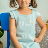 a girl in a blue dress sitting on a blue chair