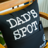 a black pillow that says dad's spot on it