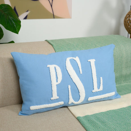 A blue throw pillow with the initials &quot;PSL&quot; embroidered on it, placed on a couch.