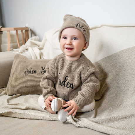 a baby sitting on a couch with a pillow