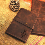 two brown leather notebooks sitting on top of a table