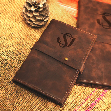 two brown leather notebooks sitting on top of a table