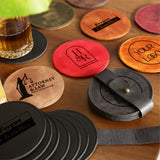 a wooden table topped with coasters and a glass