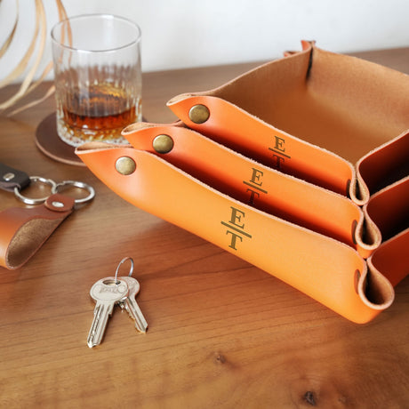a set of four orange leather wallets sitting on top of a wooden table