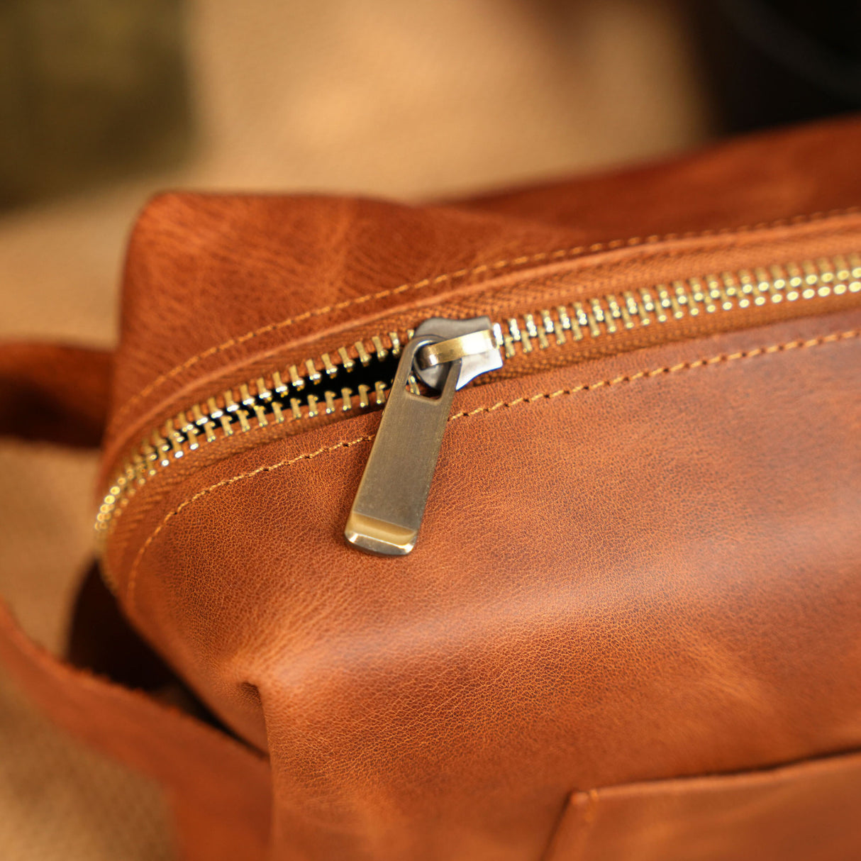 a brown leather bag with a metal zipper