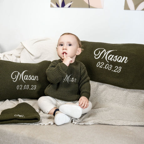 a baby sitting on a bed with two pillows