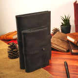 a black leather journal sitting on top of a wooden table