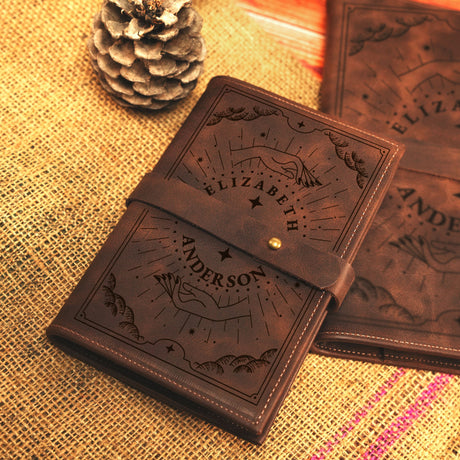 two brown leather notebooks sitting on top of a table