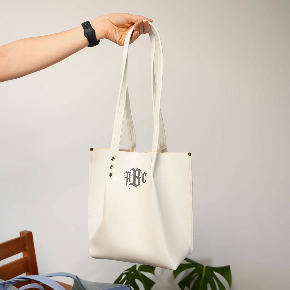 Individual holding a monogrammed white leather tote with initials