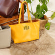 a yellow purse sitting on top of a fur rug next to a potted plant