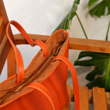 an orange purse sitting on top of a wooden chair