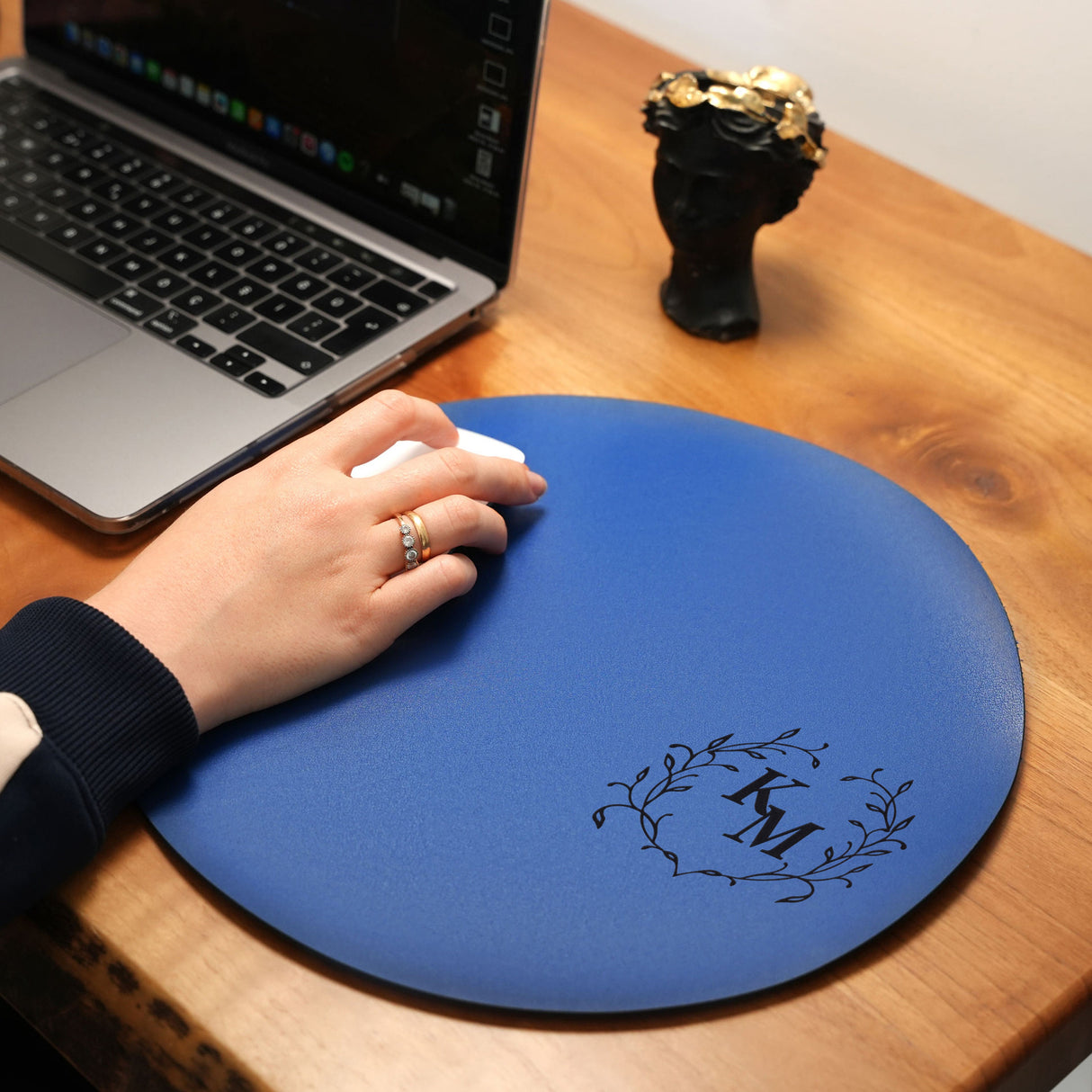 a person&#39;s hand on a mouse pad next to a laptop