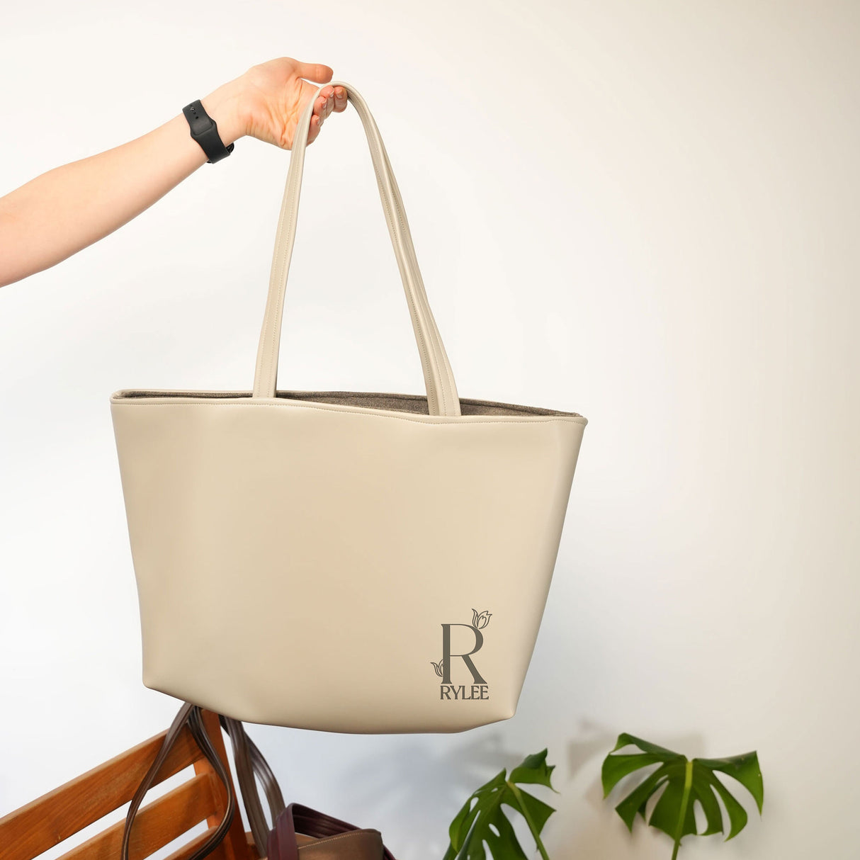 a person holding a beige bag on top of a wooden chair