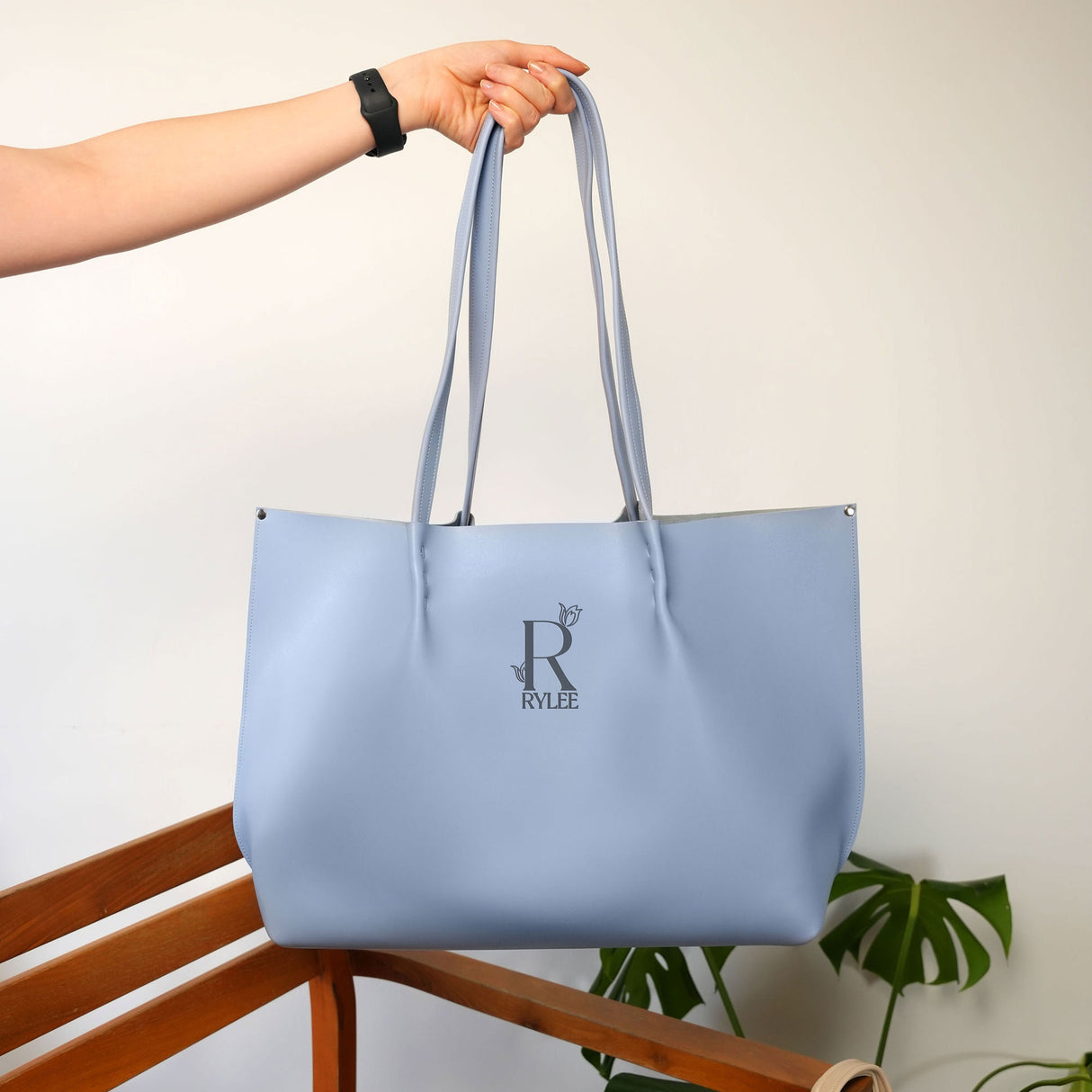 a person holding a blue bag on a wooden chair